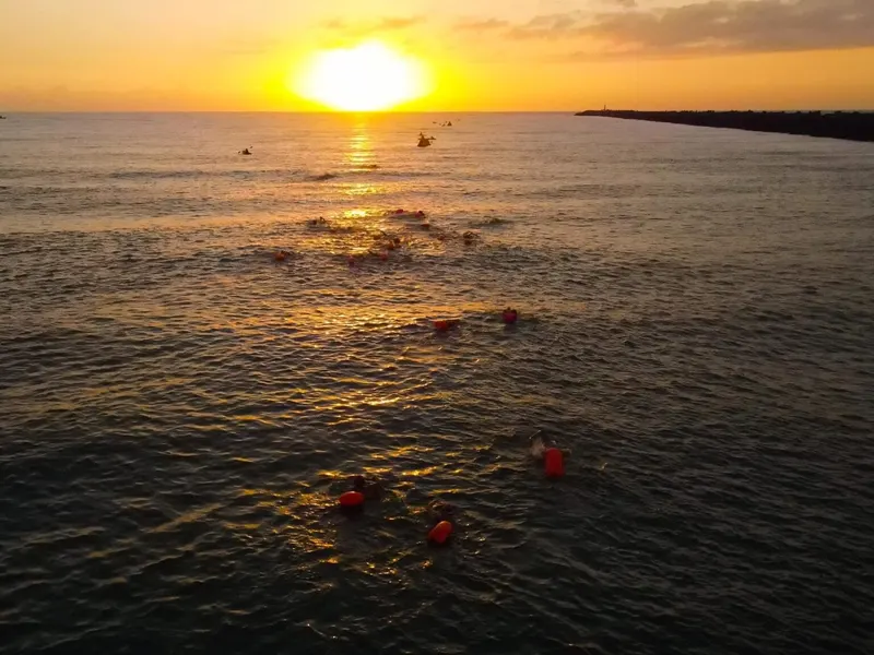 Nadadores con gorra naranja en el mar al amanecer, en Playa Miramar.